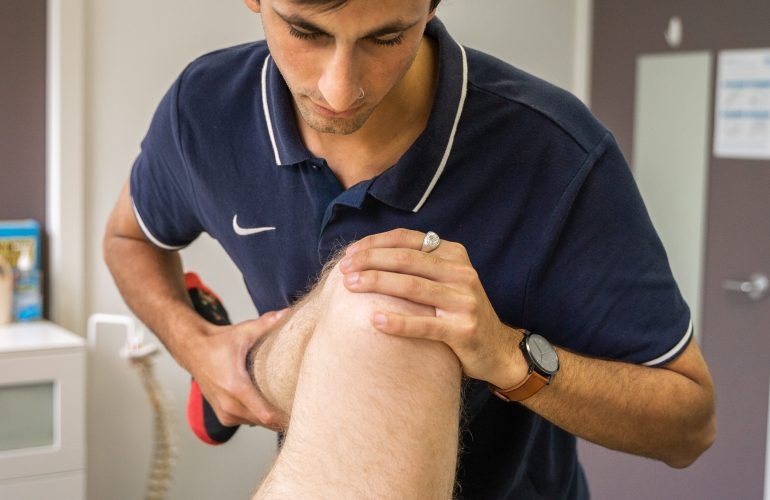 An Infinity Health and Osteo osteopath assessing a patient's knee during a consultation